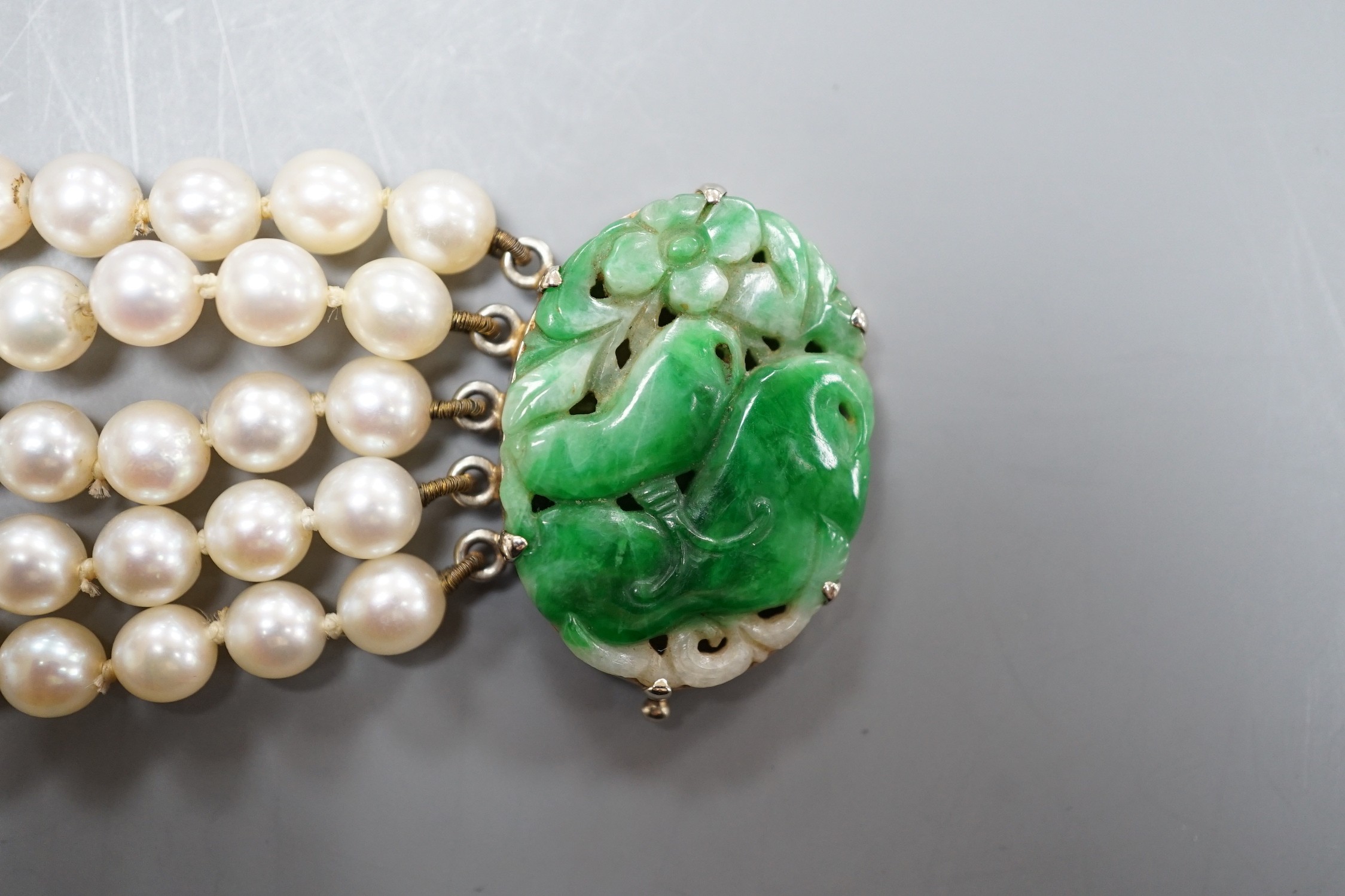 A quintuple strand cultured pearl bracelet, with carved jade set 9ct white metal clasp, 17cm, gross weight 42.5 grams, pearl diameter approx. 5.6mm.
